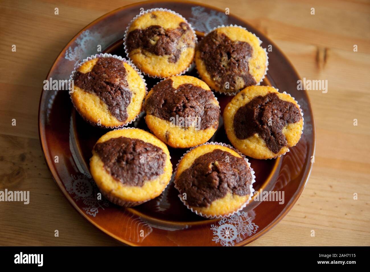 Lemon chocolate homemade muffins, few duo taste delicious cupcakes lying on dark brown plate on table, sweet treats view from above, baked food. Stock Photo