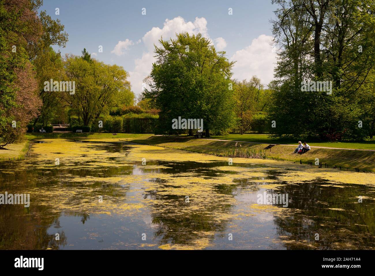 Tourists sitting by the garden pond in Nieborów Park in springtime, view at the ornamental garden in Poland, Europe, leisure time and natural bucolic Stock Photo