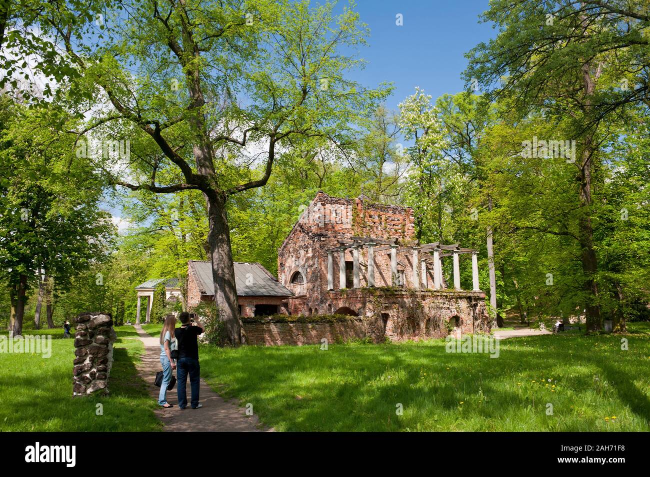 Przybytek Arcykapłana building wide view, couple taking photo of the High Priest Sanctuary in the Romantic Park in Arkadia, Poland, Europe, red bricks Stock Photo