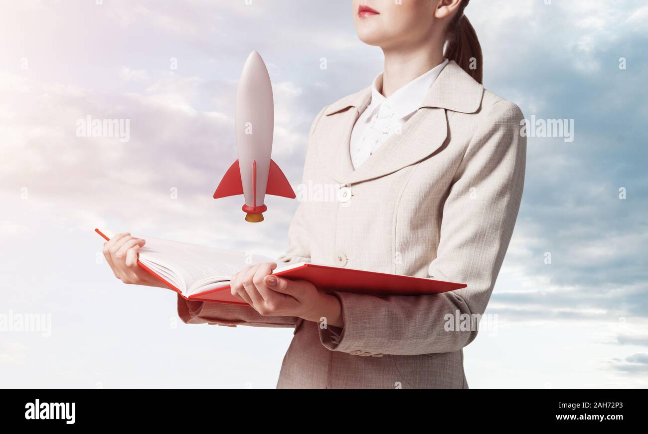 Woman showing rocket ship on open book. Rocket launch as symbol startup ...
