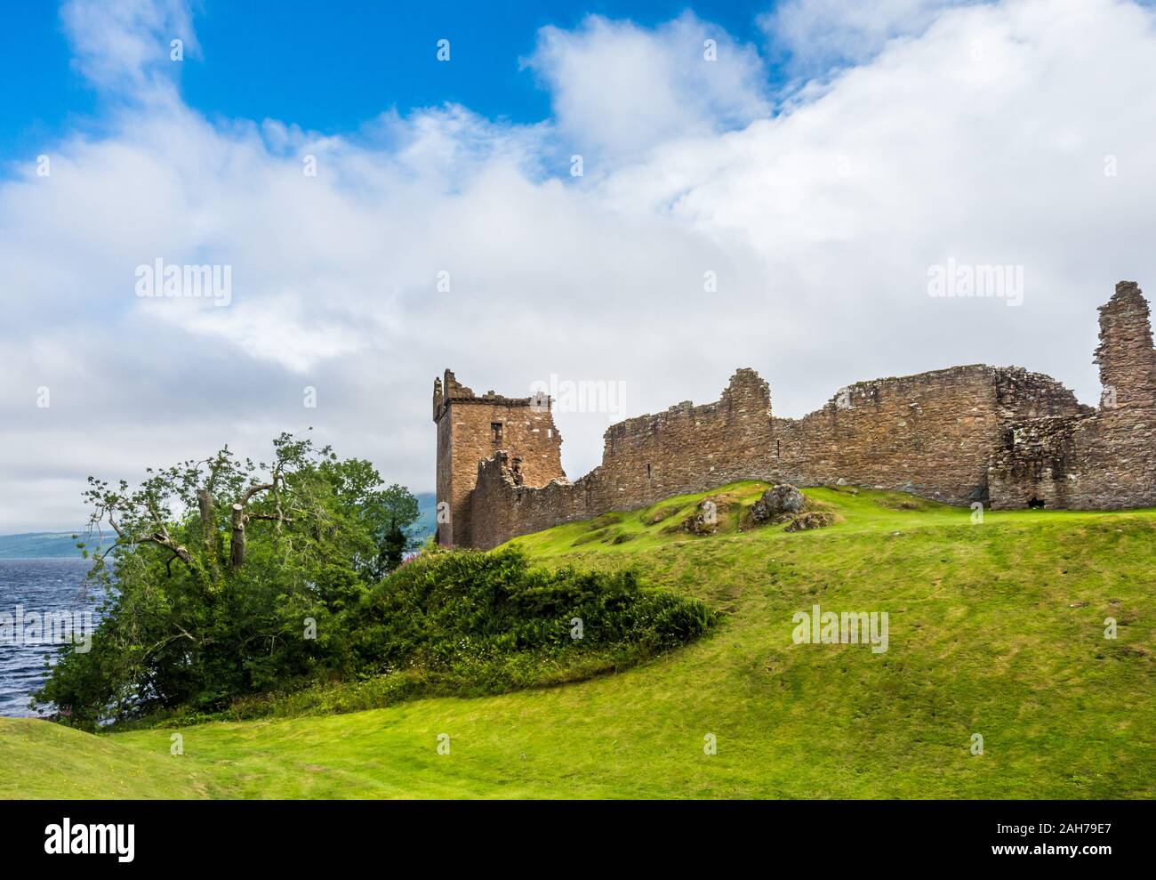 Close up of the ruins of an ancient scottish castle standing on a green hill and overlooking a lake Stock Photo
