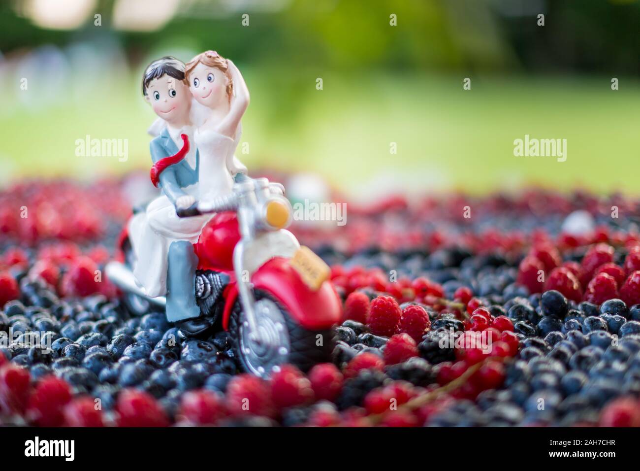 Close up of a colorful fruit wedding cake with the action figures of bride and groom riding a moped Stock Photo