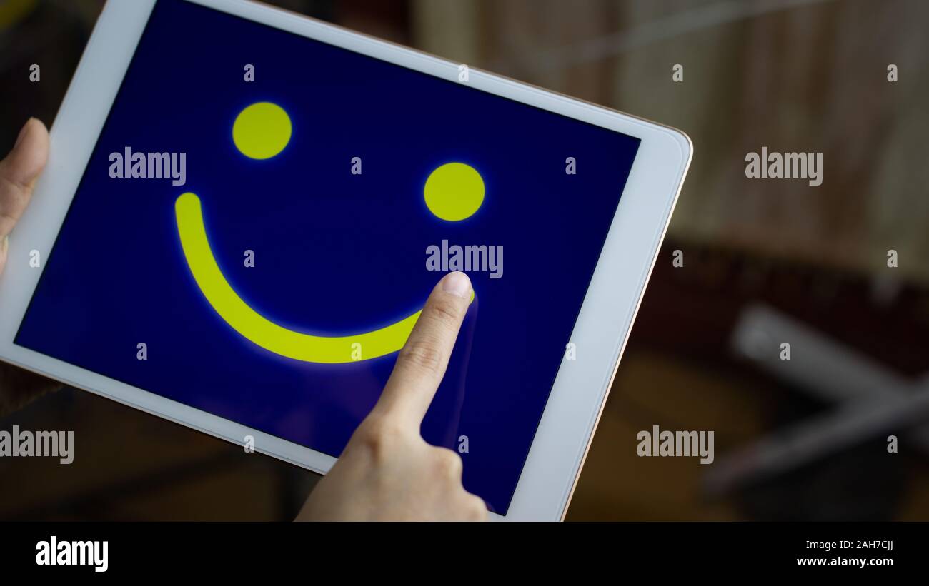 Conceptual the customer responded to the survey. The client using hand drawing  smile face on screen. Depicts that customer is very satisfied. Service Stock Photo