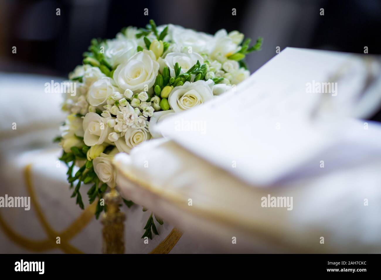 Close up of a bouquet of white roses lying on a church pew adorned for a wedding Stock Photo