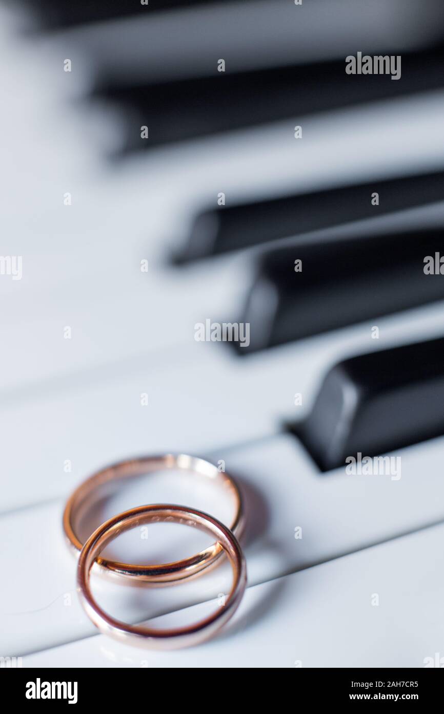 Close up of two golden wedding rings lying on a grand piano keys Stock Photo