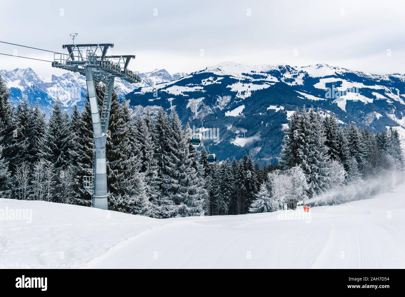 Mountains ski resort Zell am See Kaprun, Austria. Beautiful white winter landscape with snow, cable car over fir tree forest and snow cannon in snow-c Stock Photo