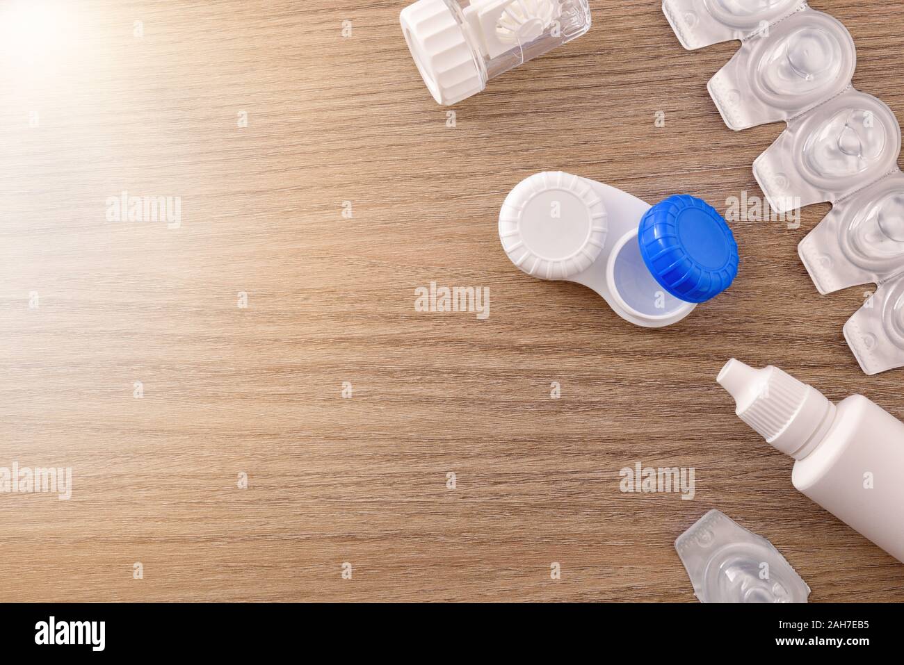 Contact lenses containers and solutions on wood table. Horizontal