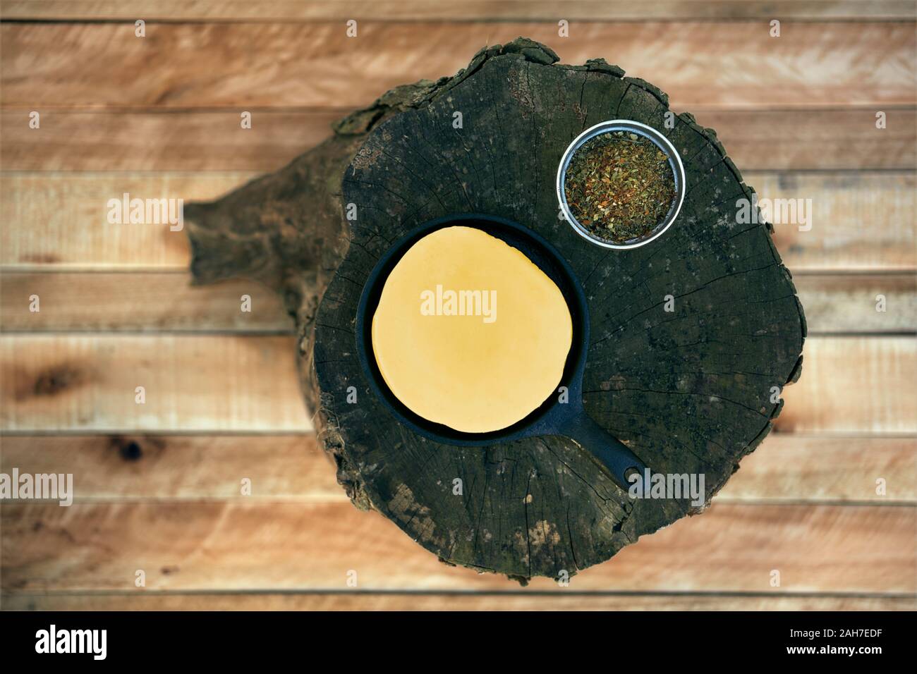 Delicious Argentinian Provolone Yarn Cheese (Provoleta) with spieces over an old log on a wooden surface, province of Buenos Aires, Argentina. Outdoor Stock Photo