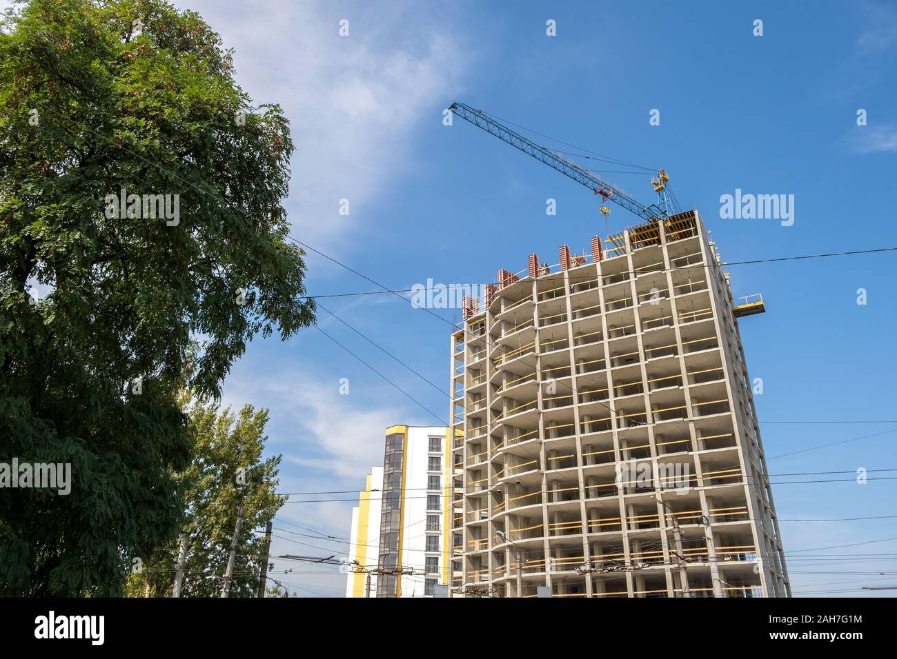 Concrete frame of tall apartment building under construction and tower ...