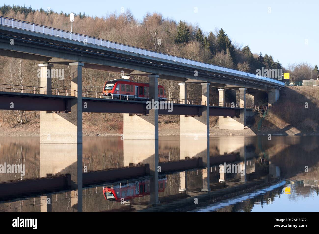 A train driver under a bridge over a lake on a sunny day. Stock Photo