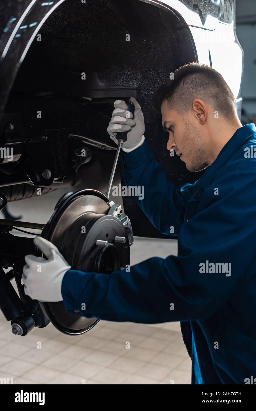 attentive mechanic adjusting brake caliper with screw driver Stock