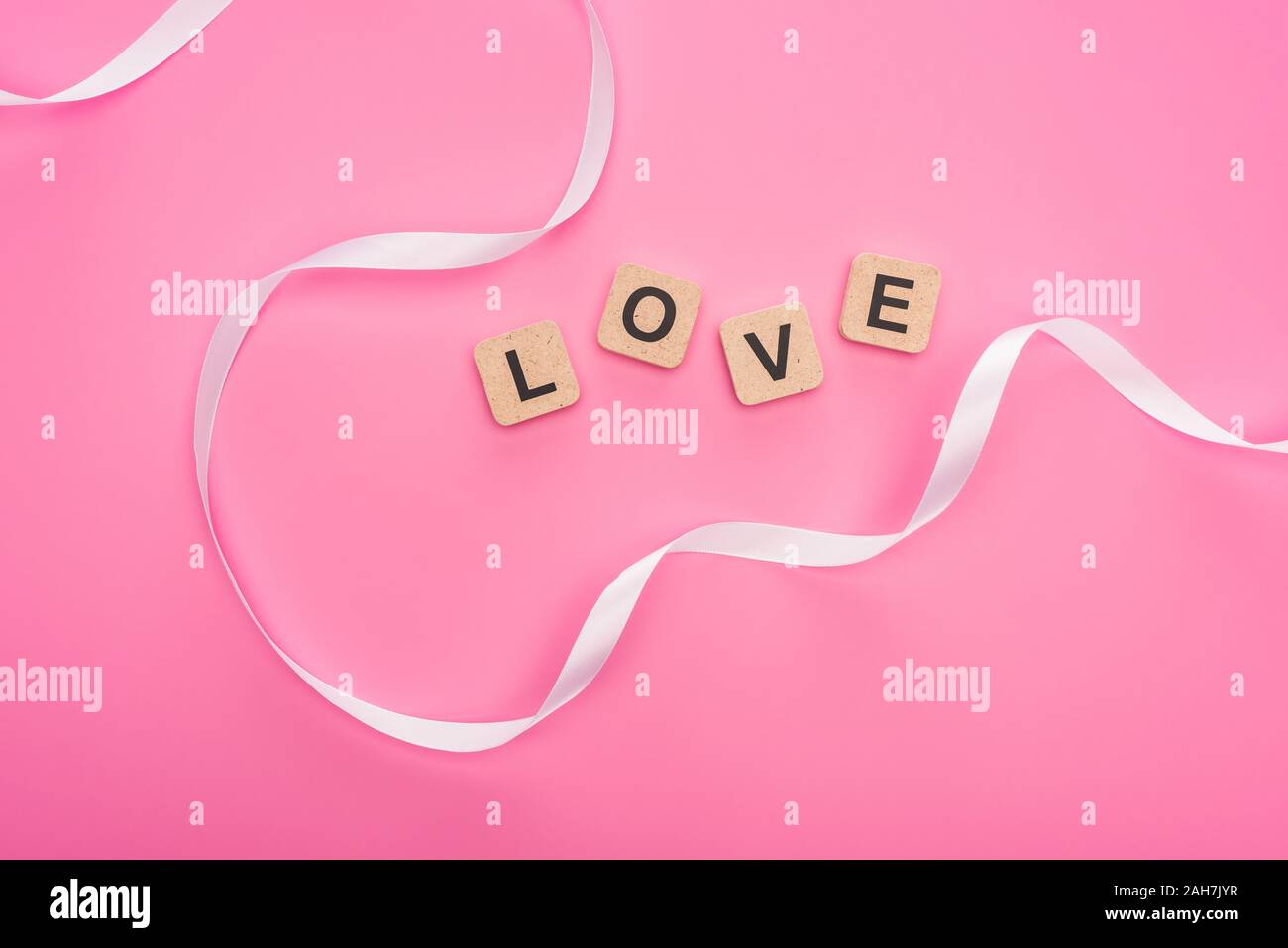 top view of curved ribbon and wooden blocks with love lettering ...