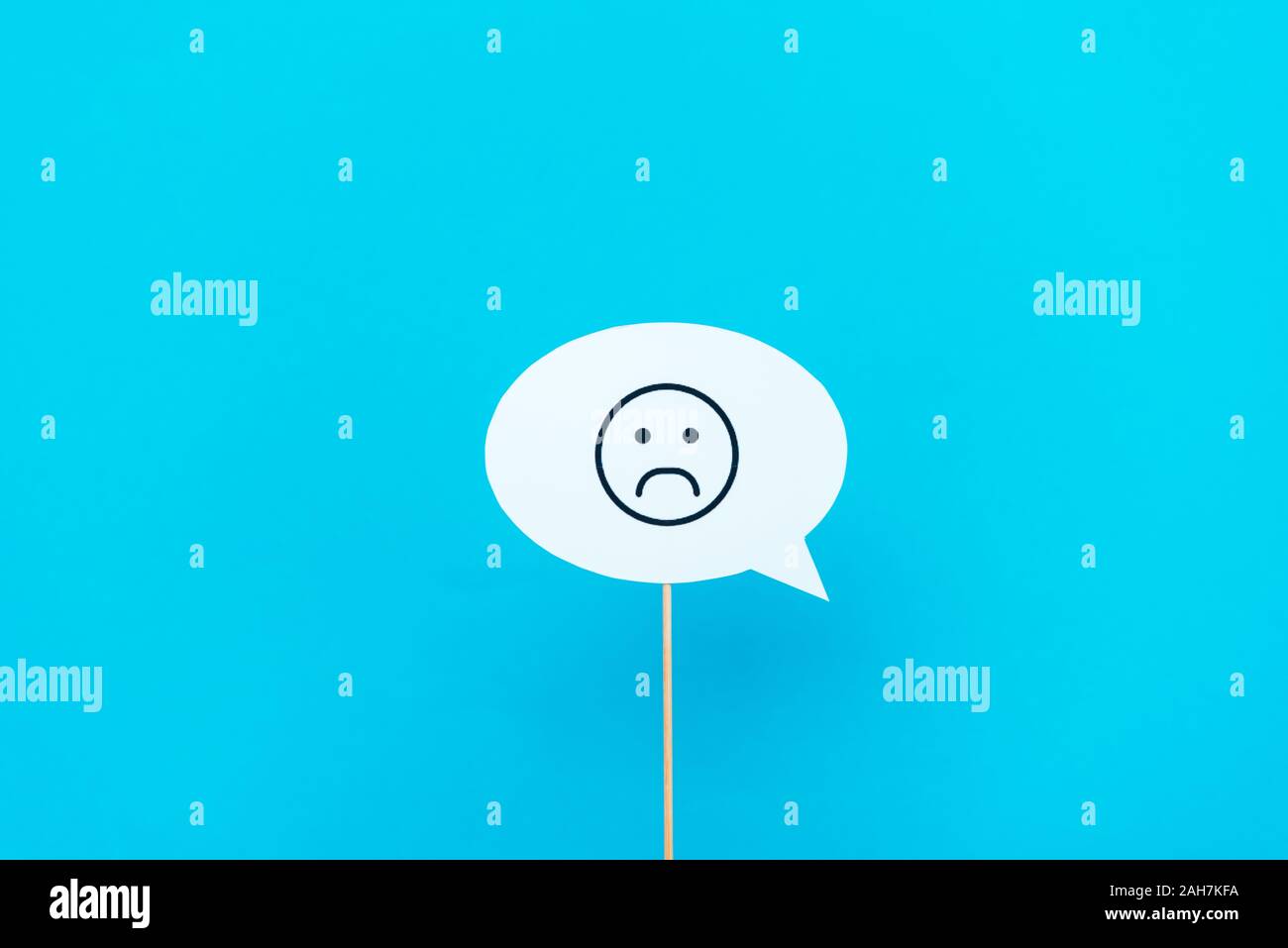 KYIV, UKRAINE - AUGUST 5, 2019: sad emoticon on stick and speech bubble isolated on blue Stock Photo