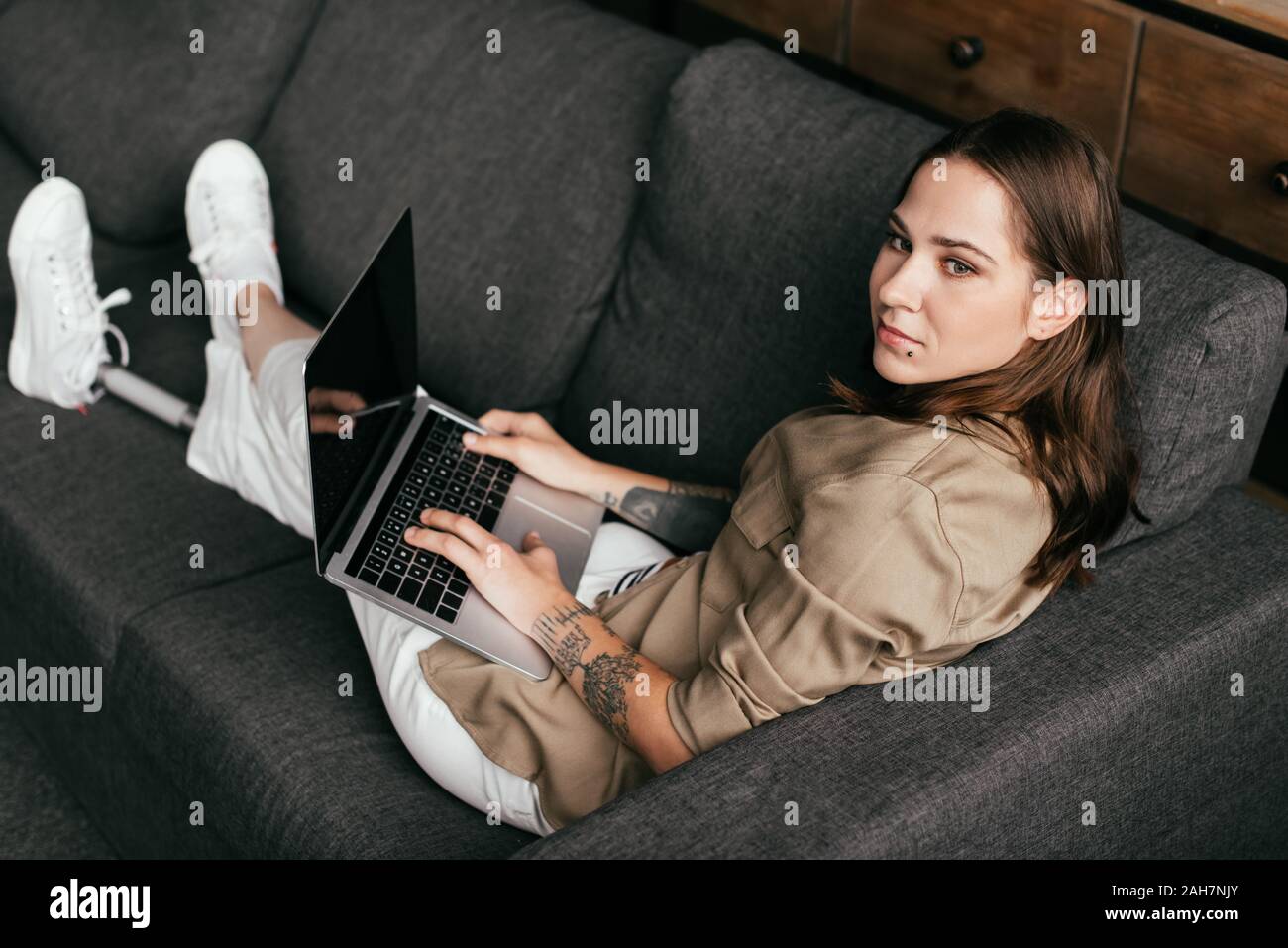 Beautiful girl with prosthetic leg using laptop with blank screen