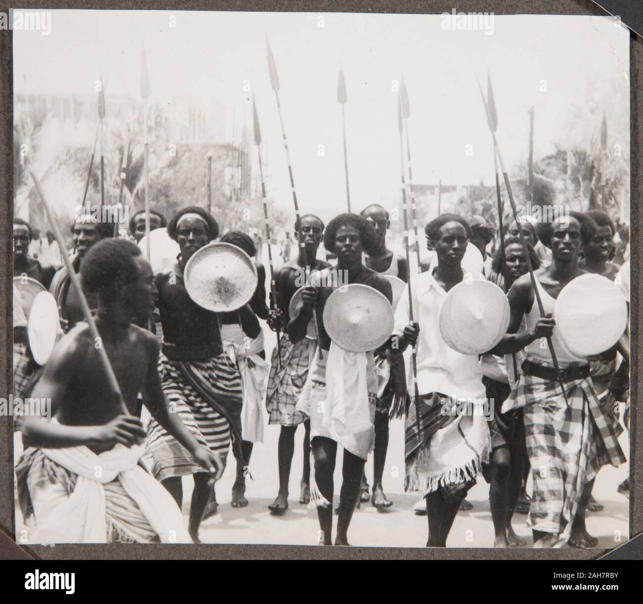 Somalia, A group of Somali men advance towards the camera carrying spears and shields. This is similar to another image described as a Bimal war dance, Kismayo, circa 1940. 2000/084/1/1/3/81. Stock Photo
