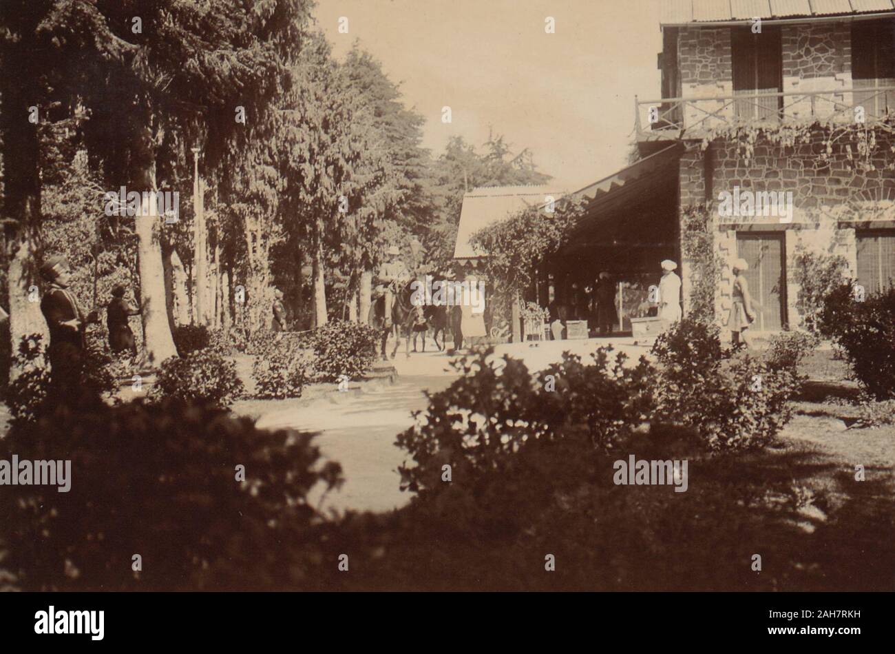 India, Exterior view of the gardens and buildings of Jandri Ghat, Dalhousie, built in 1870-71 as a residence of the Kings of Chamba. There are European guests on horseback and Indians standing in the gardens. Winthrop and Maclagan's party stayed here on the night of the 28th April on the way back from Chamba to Lahore.Original manuscript caption: Leaving Jandrighat, 29 April 1920. 2001/243/1/1/3/82. Stock Photo