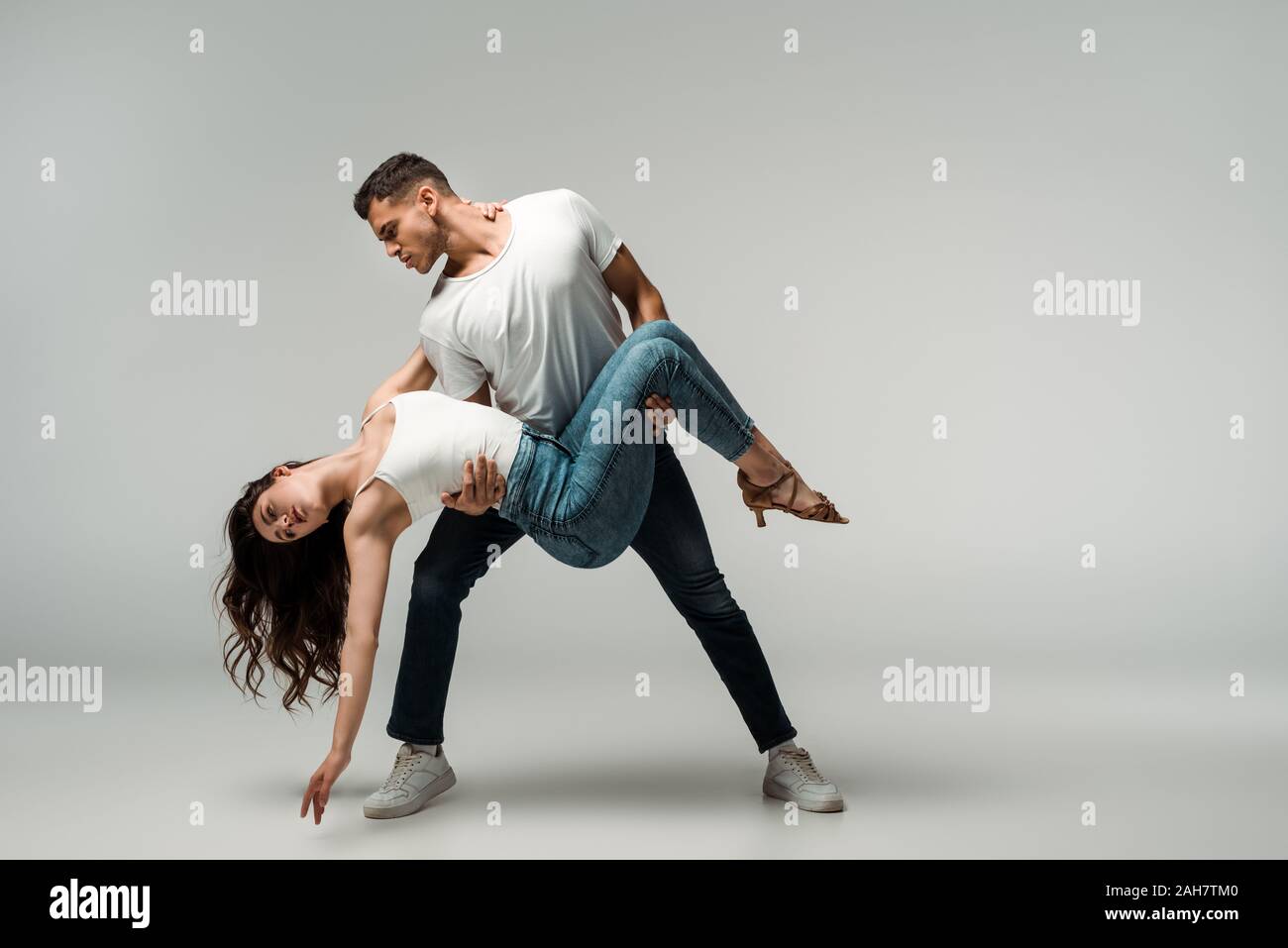 dancers in denim jeans dancing bachata on grey background Stock Photo