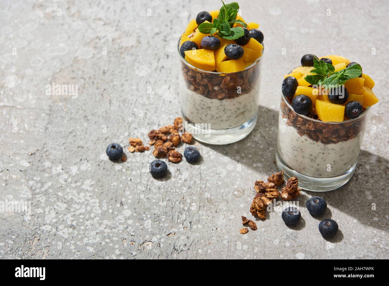 tasty granola with canned peach, blueberries and yogurt with chia seeds on grey concrete surface Stock Photo