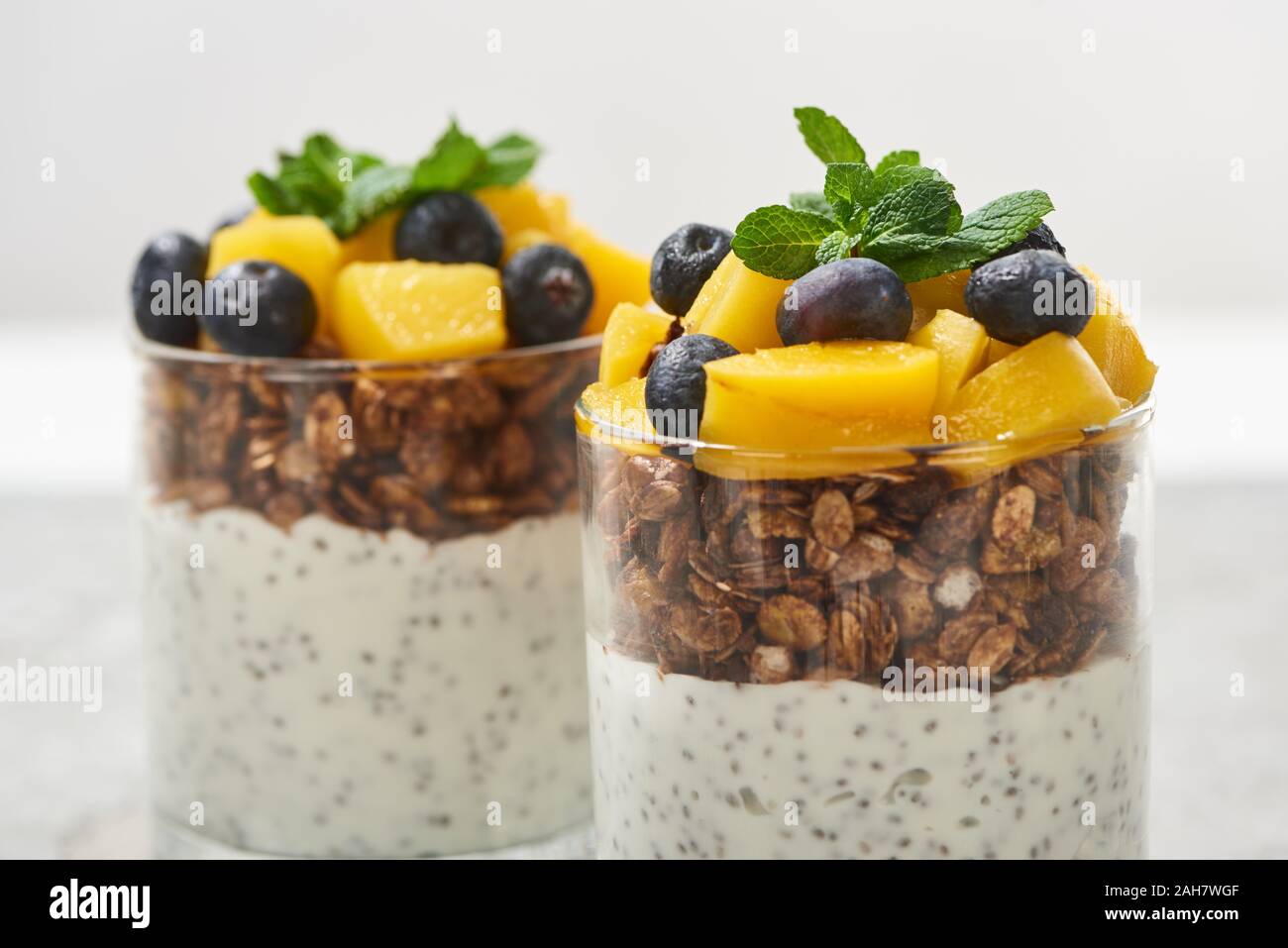 close up view of tasty granola with canned peach, blueberries and yogurt with chia seeds Stock Photo