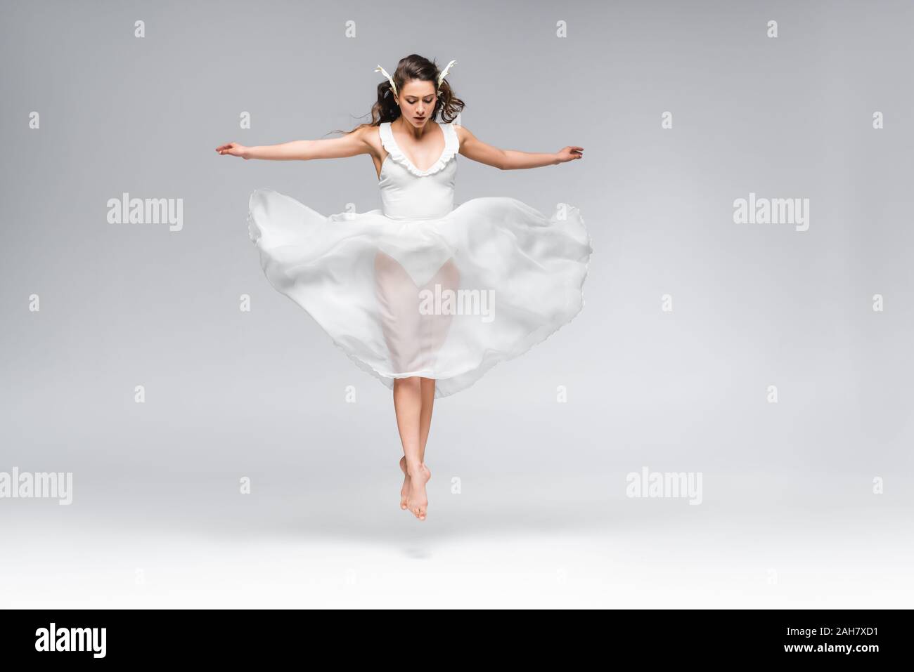 Она танцует в белом платье смотрит тайно. Танцовщица в белом платье. Балерина в белом платье. Танцовщица на сером фоне. Белое танцевальное платье.