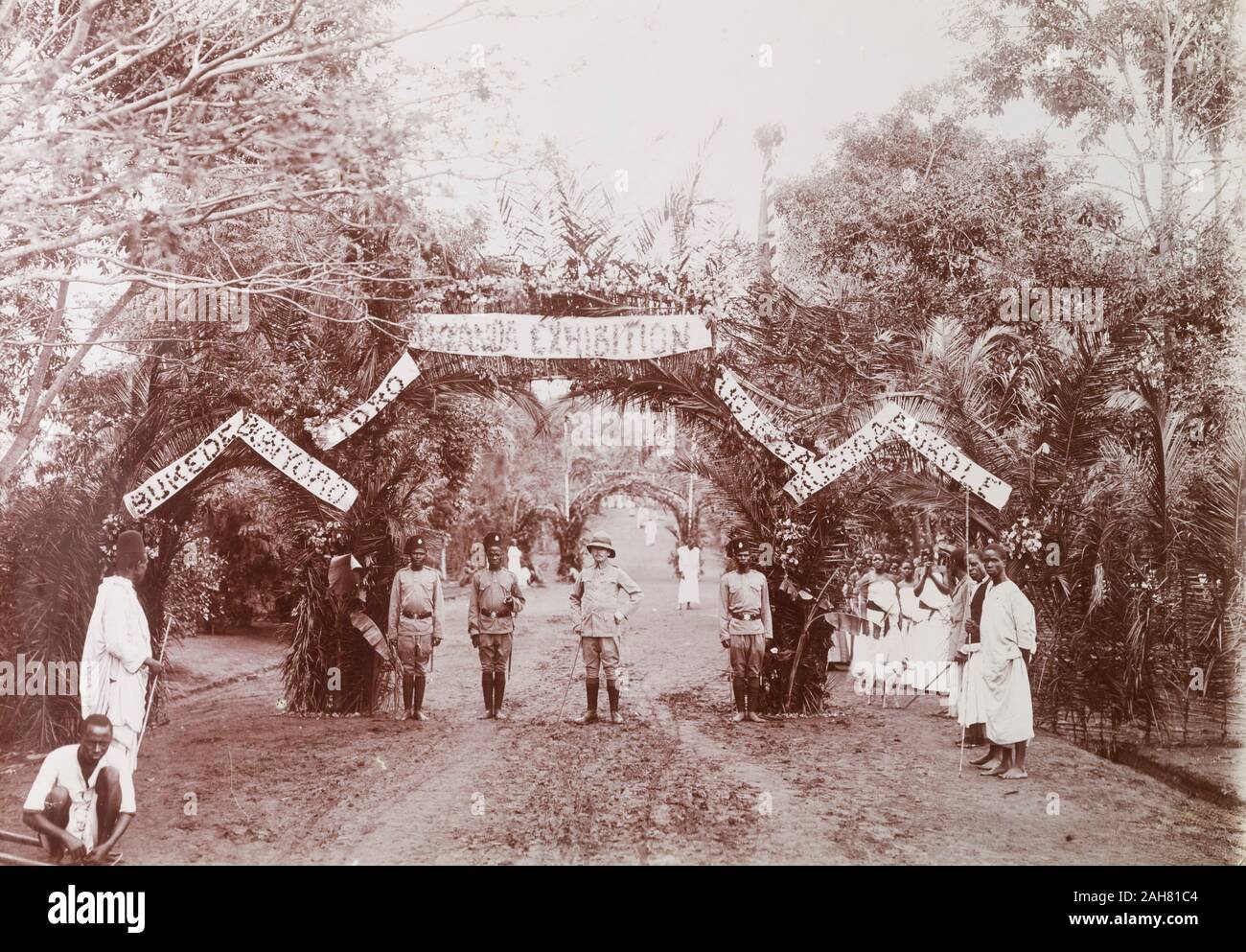Uganda, The entrance to the Uganda Exhibition, fashioned from tied palm leaves and adorned with banners, is guarded by askaris.Original manuscript caption: Uganda Exhibition at time of King Georges Coronation, [1936]. 2001/090/2/2/2/1/2. Stock Photo