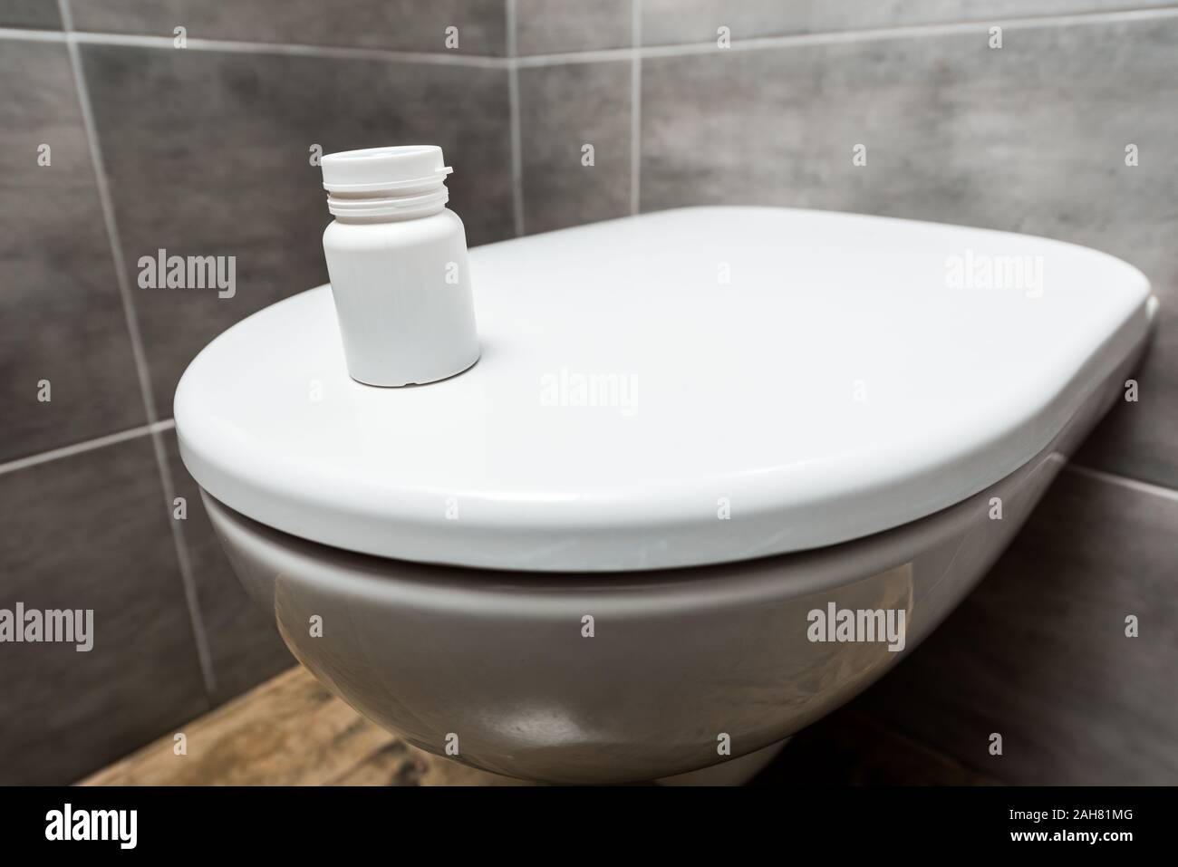container with pills on ceramic clean toilet bowl in modern restroom