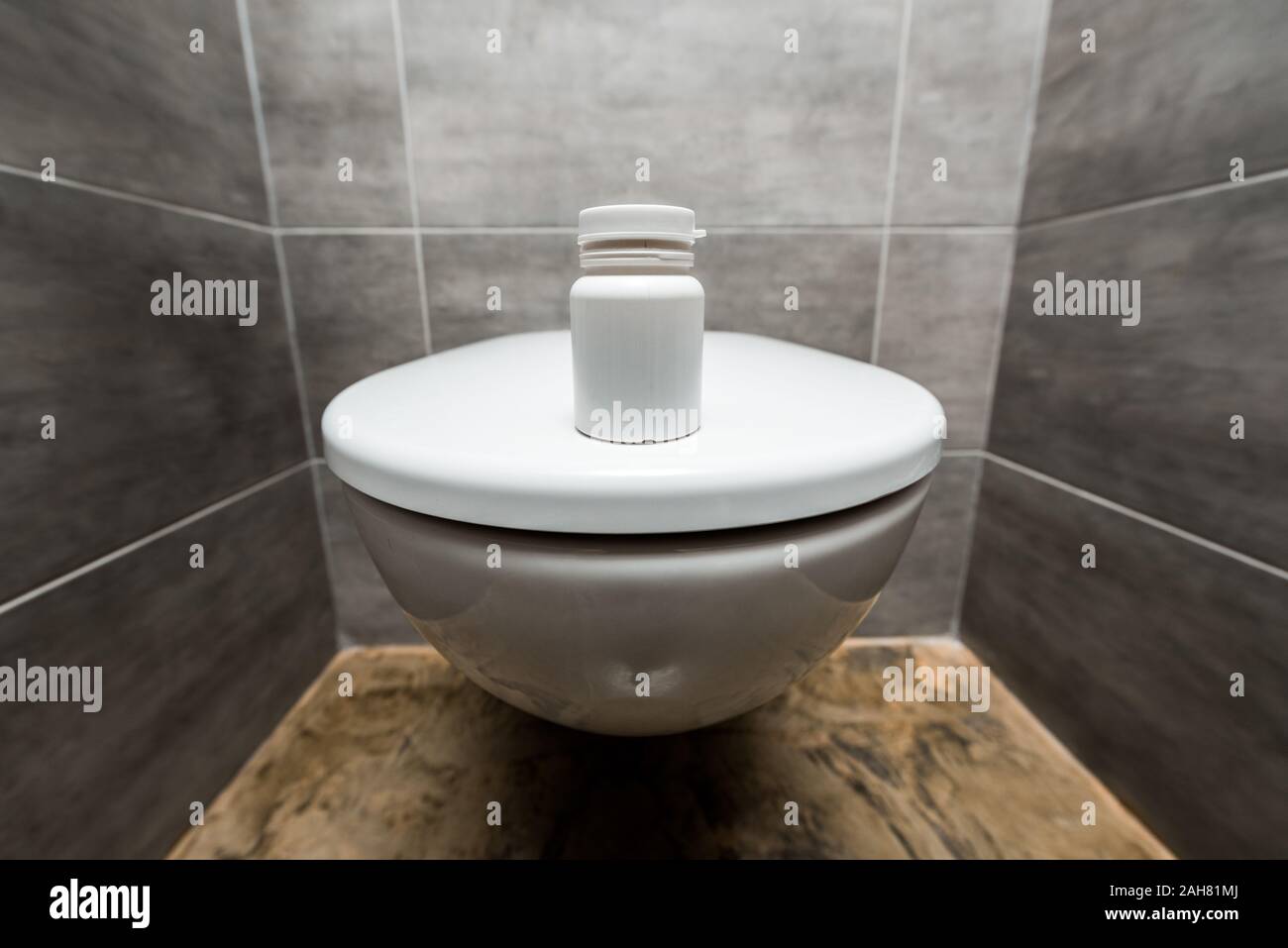 container with pills on ceramic clean toilet bowl in modern restroom