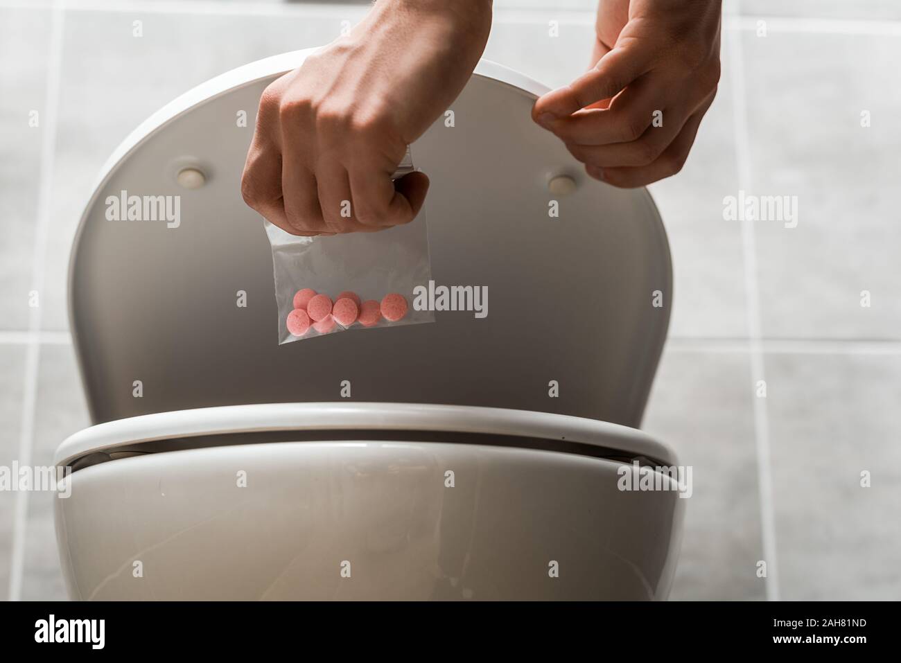 Hand throwing pills down a toilet Stock Photo - Alamy