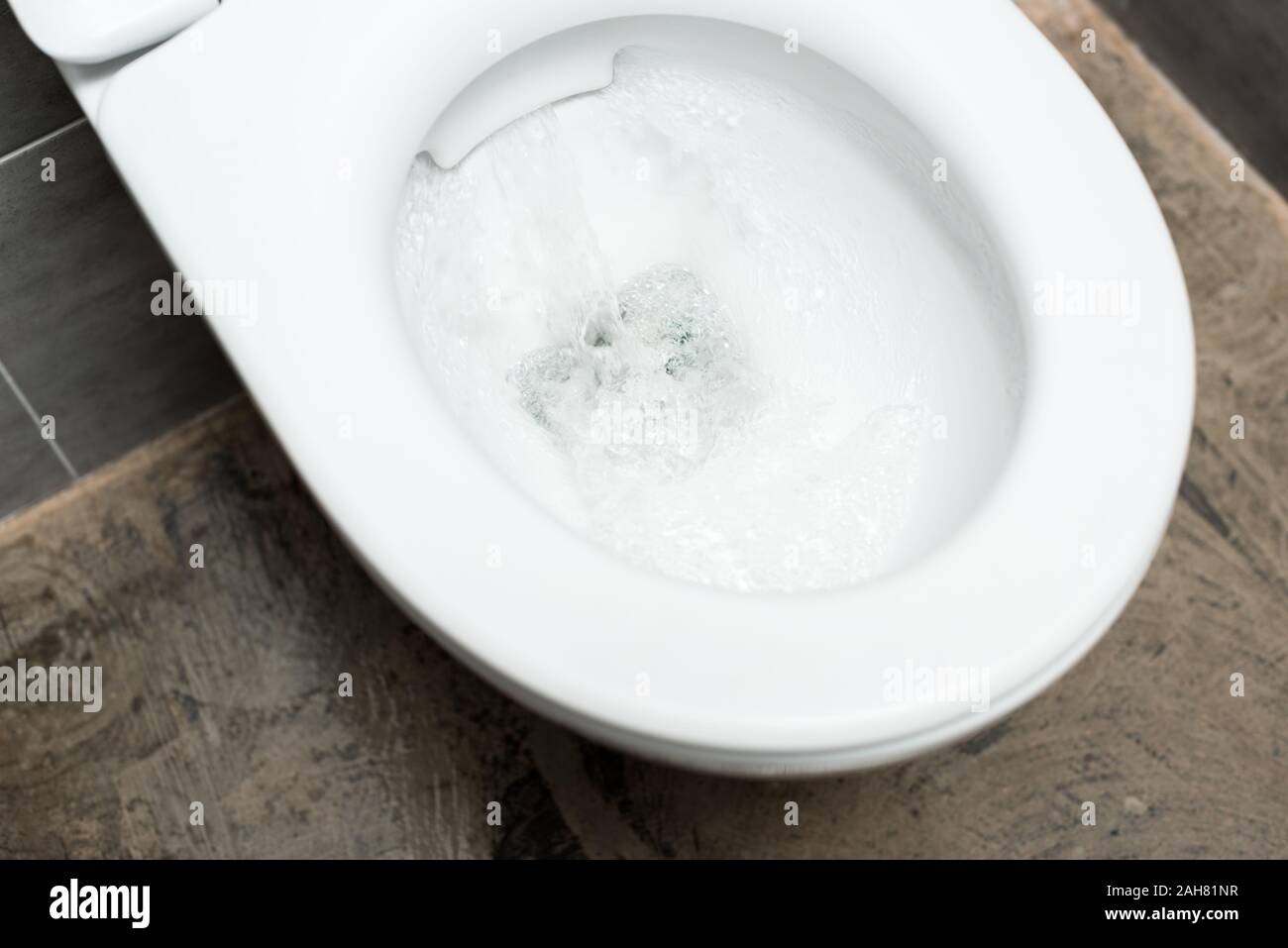 clean white toilet bowl with flushing in modern restroom with grey tile Stock Photo Alamy