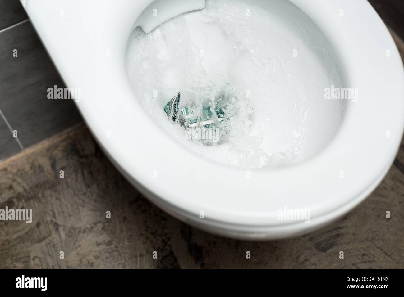 clean white toilet bowl with flushing money in modern restroom with grey tile Stock Photo Alamy