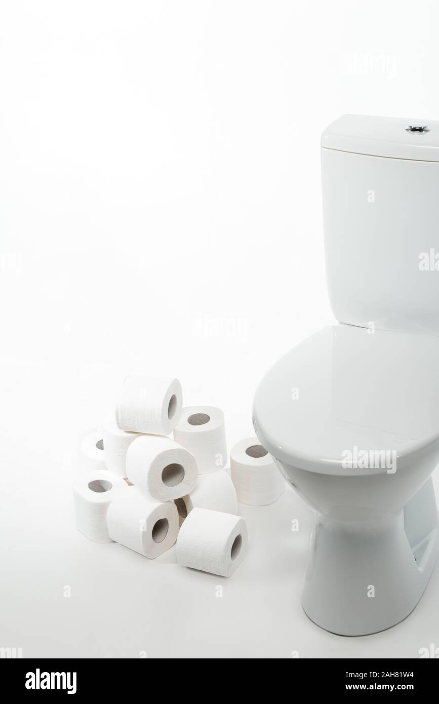 ceramic clean toilet bowl with rolls of toilet paper on white ...