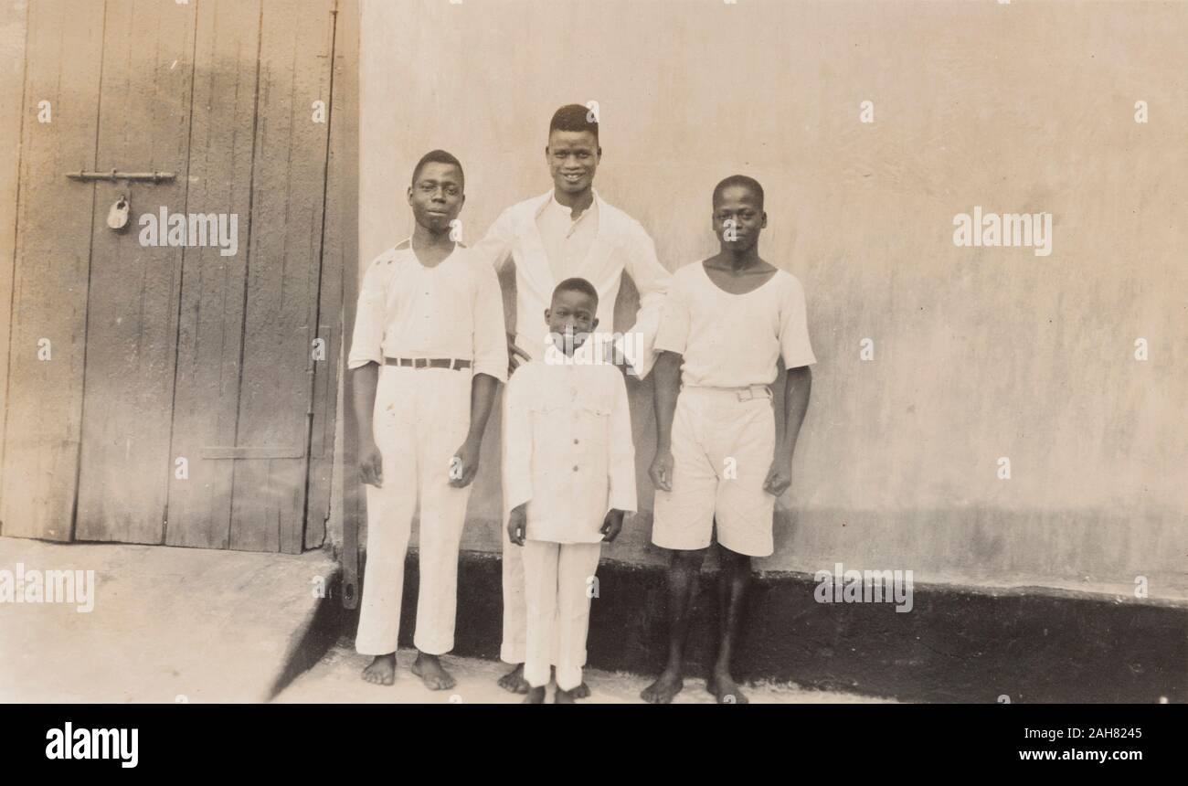 Nigeria, Caption reads: 'Mrs Flack's house staff'. Domestic servants pose for the camera against a wall. There are 3 young African men and a boy called Edward, [c.1920s]. 2000/098/1/108. Stock Photo
