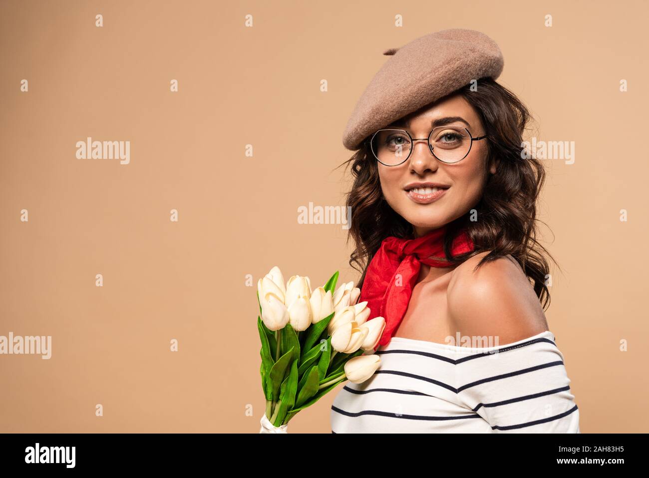 french woman in beret holding bouquet on beige background Stock Photo