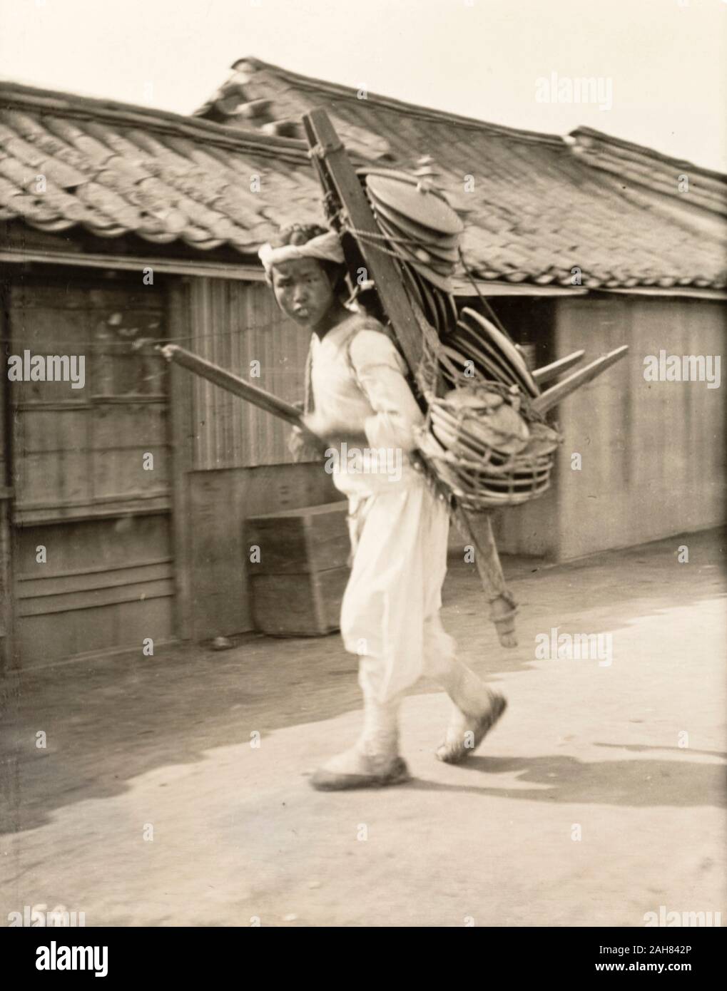South Korea, A Korean peddler boy carries his wares, probably crockery of some kind, on a wooden frame strapped to his back. Original manuscript caption: Seoul, Korea - Boy coolie - peddlar, circa 1920. 1998/028/1/1/239. Stock Photo