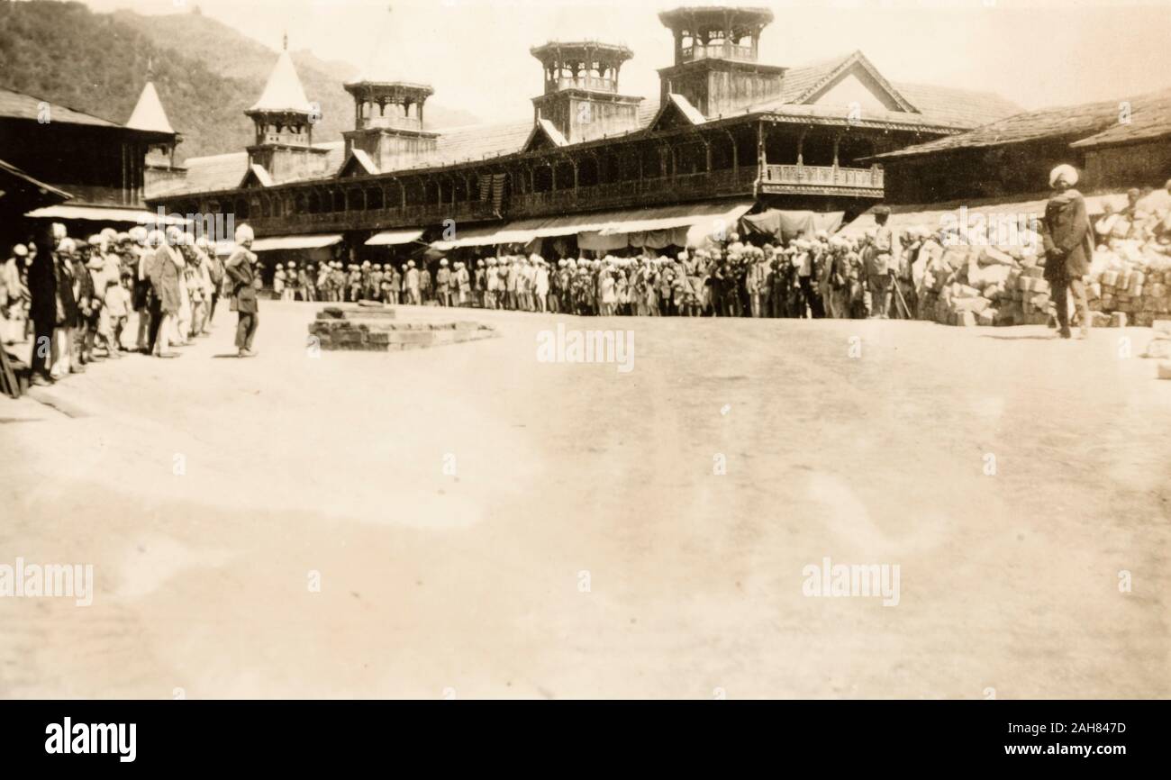 India, A crowd of people line up outside a row of shops with awnings at a chowk (road junction) in Mandi (Himachal Pradesh). They appear to be waiting for some sort of parade as the street has been totally cleared. According to Winthrop's diary he was in Mandi on that date for an Investiture with the Lieutenant Governor.Original manuscript caption: MANDI CHOWK 31/3/20, 31 March 1920. 2001/243/1/1/3/27. Stock Photo