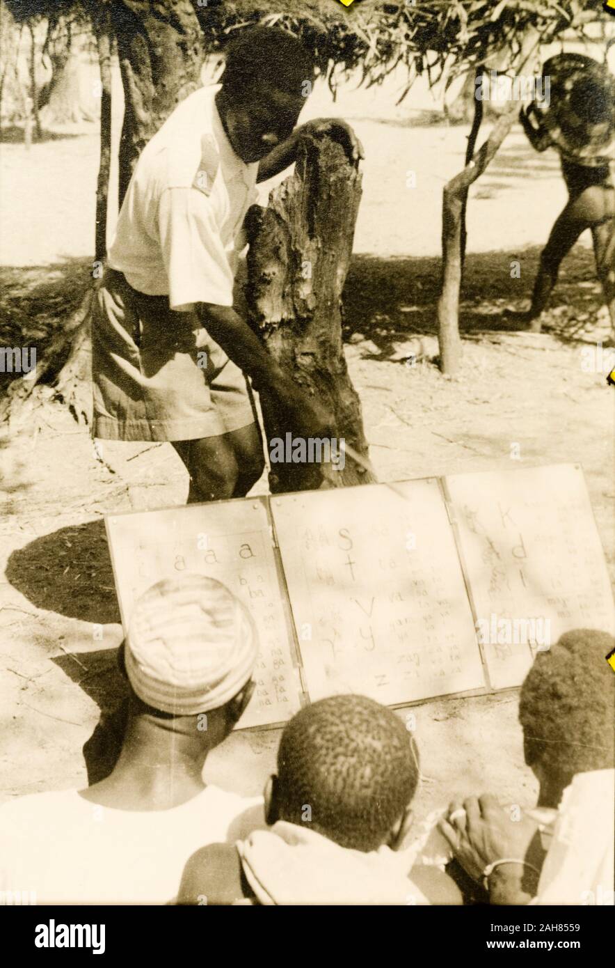 Gold CoastGhana, A student teacher helps men to read from a board during a literacy class; part of a mass literacy campaign launched by the British government in 1951 to improve literacy skills amongst African adults, both in their own languages and in English. Original manuscript caption: Mass literacy class, NTs [Northern Territories], 1951-52. 1995/076/5/2/2/69. Stock Photo