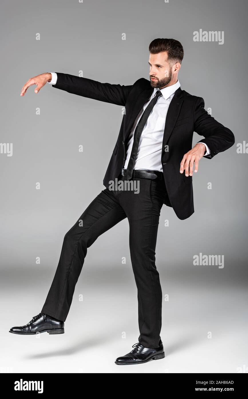 full length view of creepy zombie businessman in black suit on grey