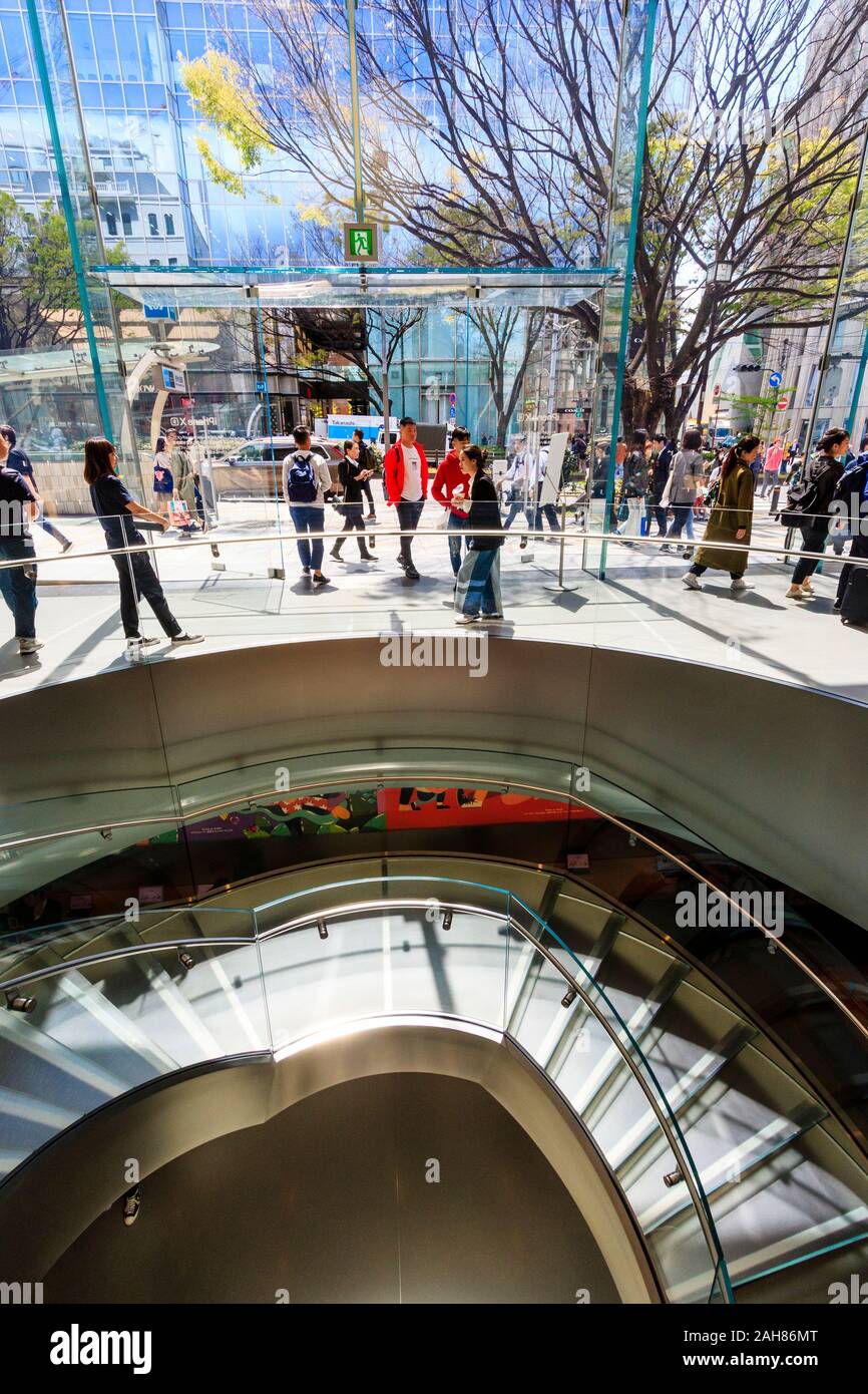 Interior of the Apple store in Omotesando, Tokyo. Spiral staircase to basement level, with the entrance top the shop in the background. Glass building Stock Photo