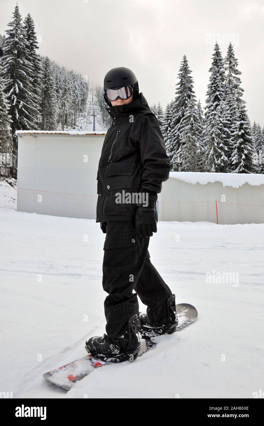 Ski skiing and snowboarding Lone young male snowboarder in black outfit  posing on winter resort ski slope Stock Photo - Alamy