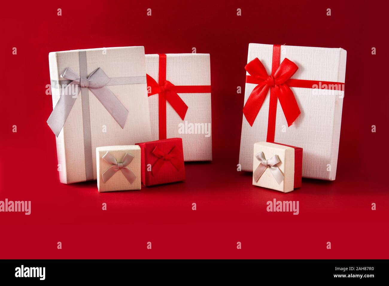 Assorted white gift boxes on red background. Stock Photo