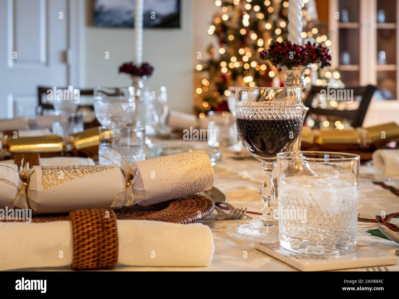 Traditional british christmas lunch table setting with crackers and glasses  with xmas tree in the background Stock Photo - Alamy