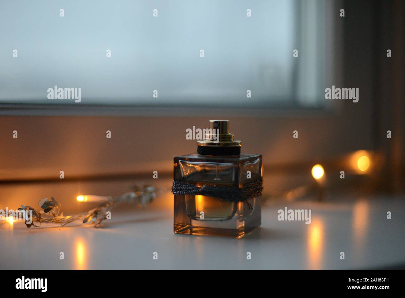 perfume bottle in a windowsill by a chain of christmas lights Stock Photo