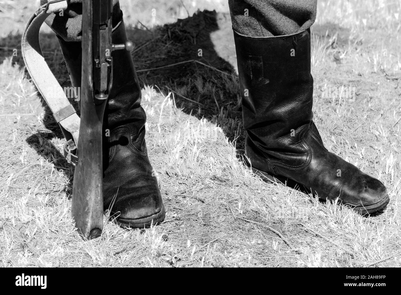 Soldier in boots with gun on countryside. Stock Photo