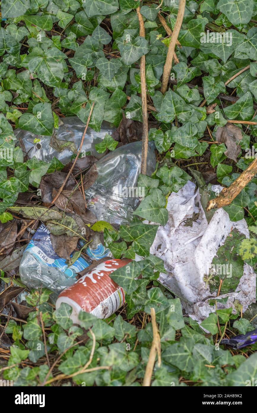 Pile of single use plastic food packaging littering a corner of the countryside. Many brands so RM editorial only. Polluted countryside UK. Stock Photo