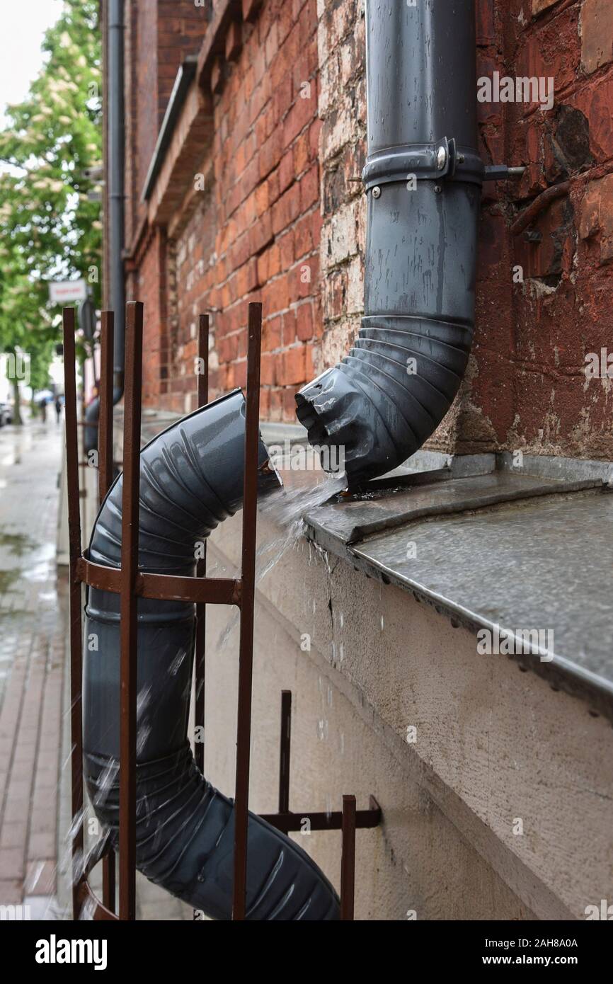 Rain water flowing from damage metal gutter. Stock Photo