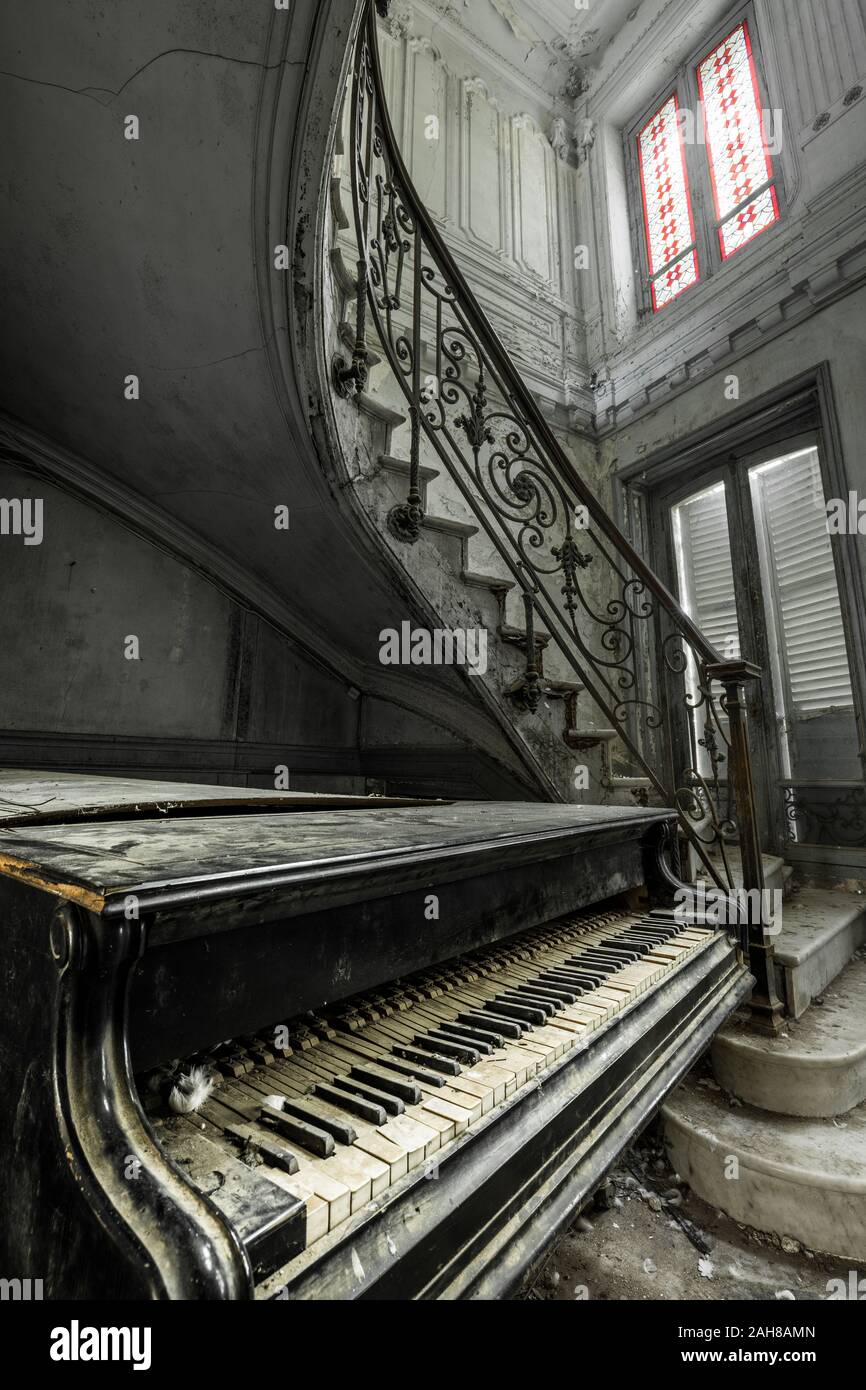 Close up view of an ancient weathered grand piano lying down the stairwell  of the spiral staircase in an abandoned french countryhouse Stock Photo -  Alamy