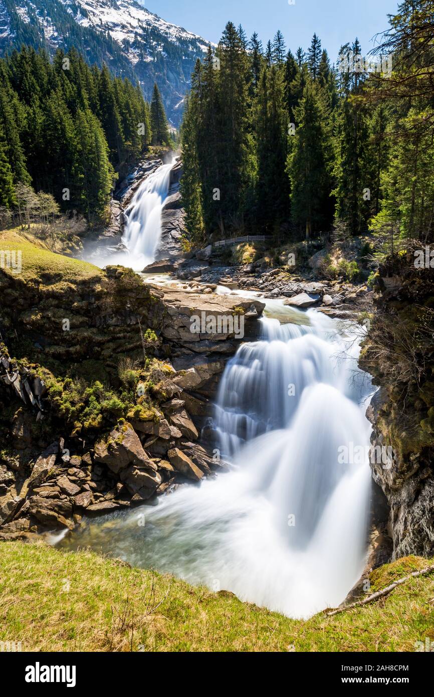 Wide angle austrian alpine landscape, with a stream running between pine trees and rocks and into double waterfall Stock Photo