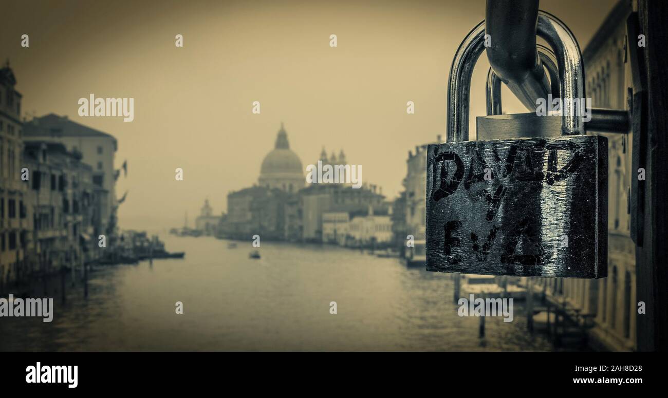 Black and white close up of a love lock on a venetian bridge, with an iconic baroque church in the background Stock Photo