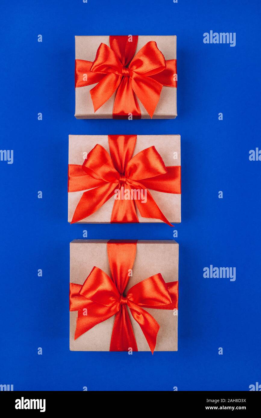 Three cardboard gift boxes with bows on blue background. Stock Photo