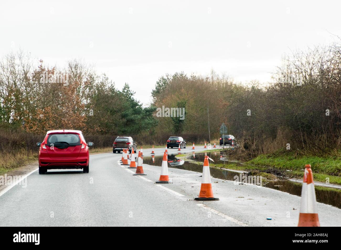A main road through part of the United Kingdom is coned off to protect drivers from driving through a flooded lane. Stock Photo